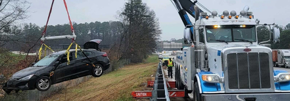 A rotator tow truck hoisting a passenger vehicle that ran off the road